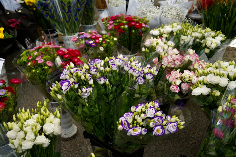 A variety of fresh flower bouquets arranged on a display table, showcasing an assortment of colours and types. Prominent among them are purple and white eustoma flowers, surrounded by pink, white, and
