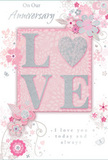 This anniversary card presents itself like a gentle love note discovered after a stroll along the canal in Hackney Wick, its design bathed in soft pastel pinks and silvery greys. At the very centre, the word LOVE stands out in raised, softly shimmering glitter, with each letter carefully shaped so the fingertips can follow their curves. The O is replaced by a silver-textured heart, slightly more reflective than the surrounding letters, giving the sense of a jewel set into the paper. Around this focal point, clouds of delicate blooms in blush, mauve, and soft white unfold across the card. Their petals appear washed in light, with a watercolour softness that blends gently into the background, while fine ink lines suggest stems and leaves curling like tendrils of ivy along Hackney Wick's brick walls. Tiny motifs-petals caught mid-fall, swirling flourishes, and almost-hidden butterflies-add a feeling of motion, as if the flowers are gently stirring in a spring breeze drifting through Victoria Park. The inscriptions On Our Anniversary and I love you today and always are rendered in a graceful script, slender and fluid, echoing the lines of the vines and enhancing the card's sense of intimacy. Together, the gentle colours, tactile glitter, and airy floral illustration create the impression of a hand-tied English garden arrangement translated into card form-understated, tender, and ideal for celebrating a shared journey, whether the card is placed beside fresh flowers on a Hackney Wick breakfast table or tucked into a bouquet delivered to a loved one nearby.